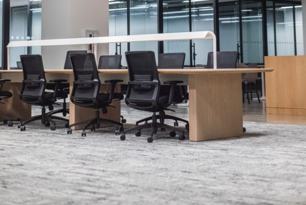 An empty office showing three black chairs and a grey carpet